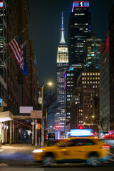 Vibrant NYC nightscape with taxi, flags and empire state