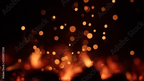 Glowing Fire Sparks and Warm Embers Bokeh Rising Against Black Background, Close-Up Shallow Depth of Field
