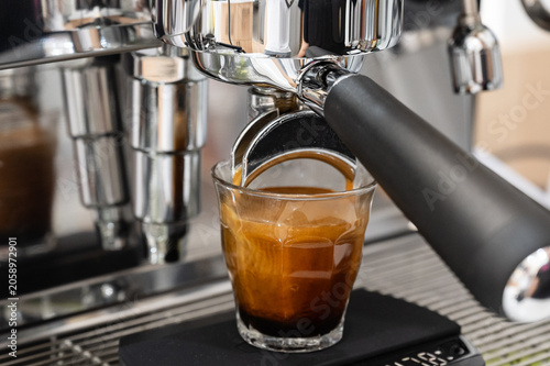 Coffee machine brewing espresso in to glass cup.Barista while preparing and working with coffee machine and making espresso coffee from arabica coffee beans.Americano pouring into a measuring cup.
