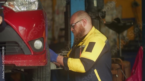 Caucasian male mechanic with glasses and a beard works alongside a female technician, reviewing a digital tablet and giving a thumbs-up. This high-energy commercial imagery represents gender diversity