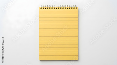 A simple yellow ruled notepad with a spiral binding sits in the center of the frame, ready for notes and ideas.