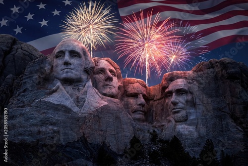 Iconic Mount Rushmore National Memorial illuminated by vibrant fireworks and the American flag.