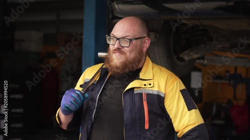 Caucasian male mechanic with glasses and a beard works alongside a female technician, reviewing a digital tablet and giving a thumbs-up. This high-energy commercial imagery represents gender diversity