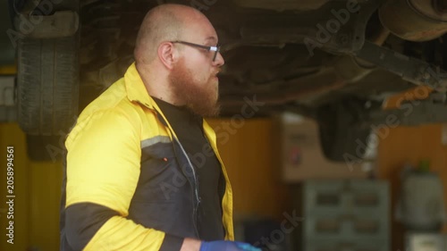 Caucasian male mechanic with glasses and a beard works alongside a female technician, reviewing a digital tablet and giving a thumbs-up. This high-energy commercial imagery represents gender diversity