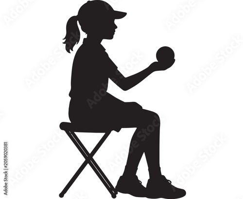 Girl silhouette wearing a cap sits on a folding stool while holding a baseball in her hand.
