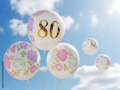 White balloons with gold 80 and floral patterns floating in blue sky.