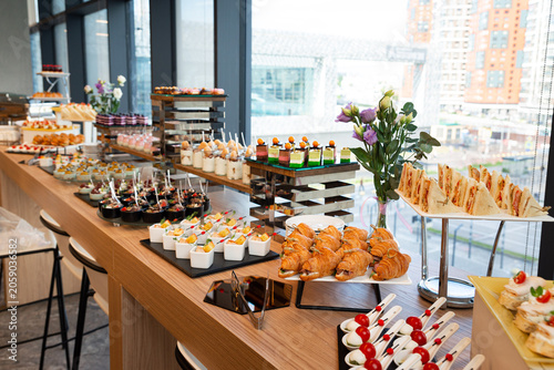 Photos Buffet table with assorted sandwiches, croissants, desserts, and appetizers for