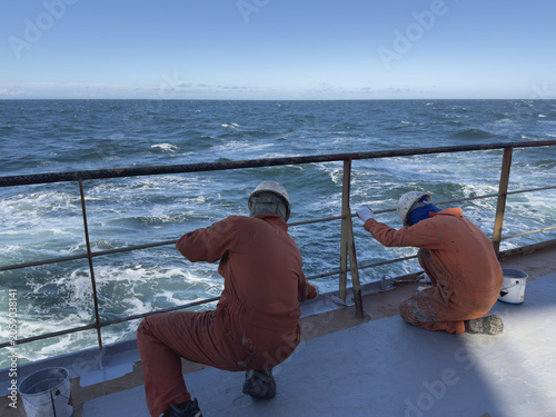 Fotografía group of seafarers in coveralls and helmets maintain the vessel