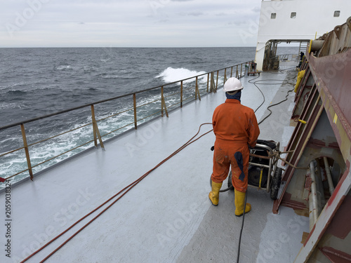 Foto marine workers, deck crew, use high pressure machine for maintenance vessel