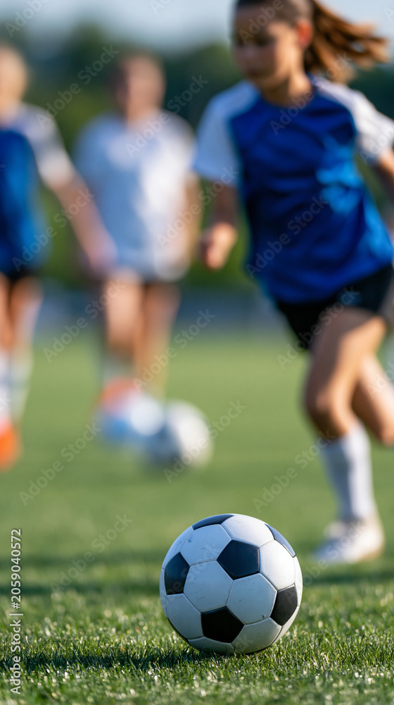 Obraz premium Faceless girls soccer team training together on a grass field, passing and dribbling drills in progress, defocused field and sky in background, youth female sports photography,