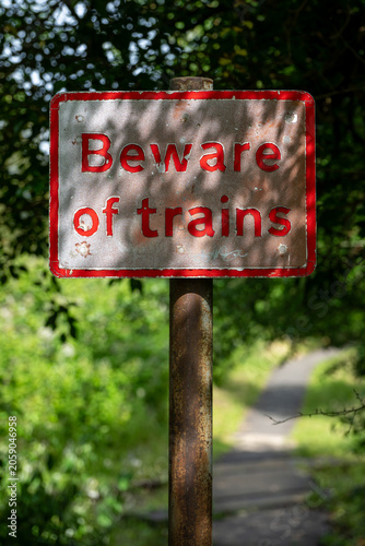 'Beware of trains' red warning sign beside a footpath railway crossing near Ashchurch, Tewkesbury, Gloucestershire