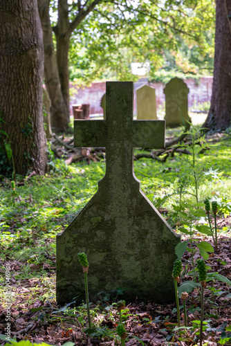 Weathered stone cross gravestone in the churchyard of Ashchurch Church, Tewkesbury, Gloucestershire, England
