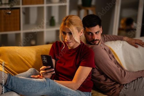Jealous man spying partner's phone in unhappy relationship