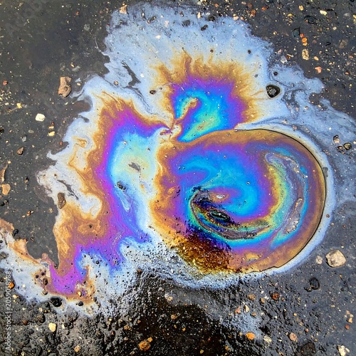A swirling rainbow-colored oil slick on wet asphalt