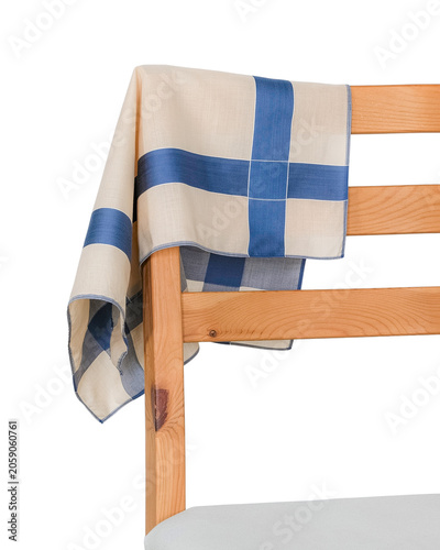 A classic beige cotton handkerchief with a minimalist blue cross pattern draped elegantly over the back of a wooden chair.