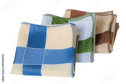 A set of folded cotton handkerchiefs featuring a minimalist cross pattern in blue, green, and brown on a textured dark background.