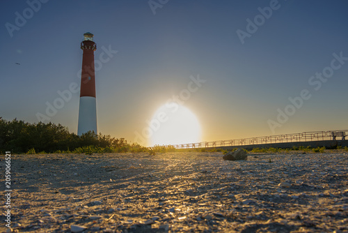 Barnegat Lighthouse at golden hour with sunburst over the beach