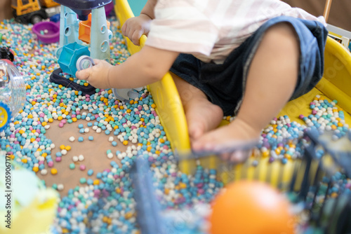 
Child plays with colorful plastic balls on yellow slide. Hands hold small tool, feet touch soft beads. Joyful, curious child explores playful, sensory environment. Perfect for preschool, therapy
