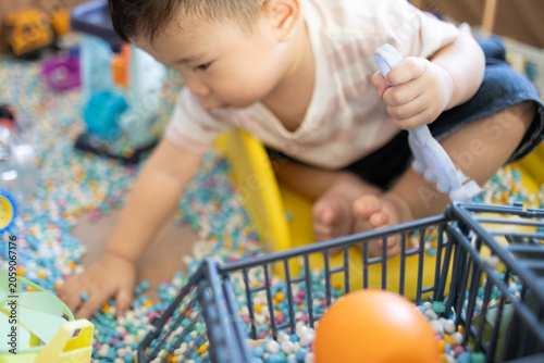 
Child plays with colorful plastic balls on yellow slide. Hands hold small tool, feet touch soft beads. Joyful, curious child explores playful, sensory environment. Perfect for preschool, therapy
