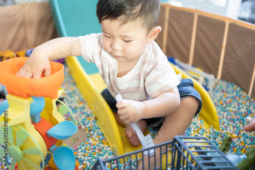 
Child plays with colorful plastic balls on yellow slide. Hands hold small tool, feet touch soft beads. Joyful, curious child explores playful, sensory environment. Perfect for preschool, therapy
