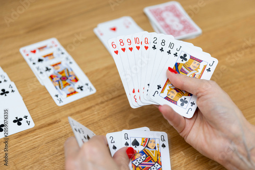 Woman's hands holding a fan of playing cards — card game, leisure, entertainment