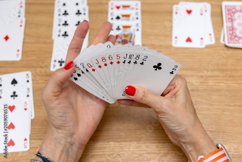 Woman's hands holding a fan of playing cards — card game, leisure, entertainment