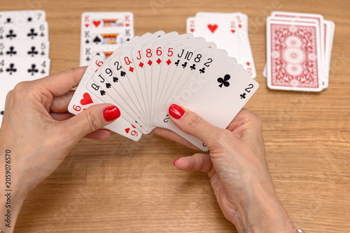Woman's hands holding a fan of playing cards — card game, leisure, entertainment