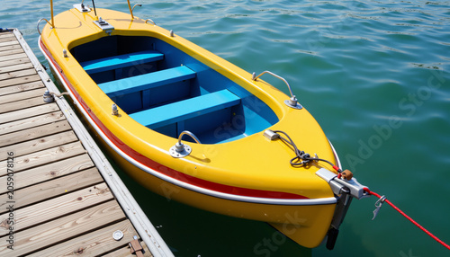 Yellow boat moored at wooden dock on clear blue water  