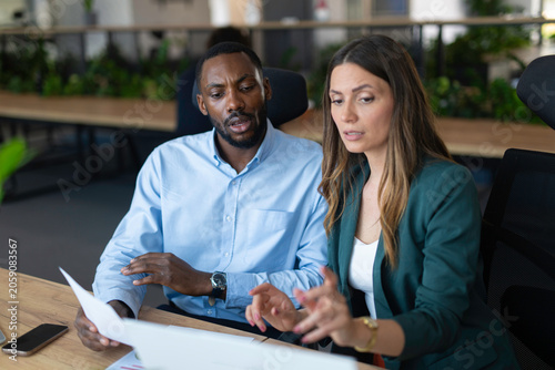 Diverse business colleagues discussing documents in modern office