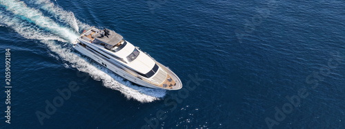 Aerial drone ultra wide photo with copy space of luxury yacht with wooden deck cruising in high speed deep blue Aegean sea