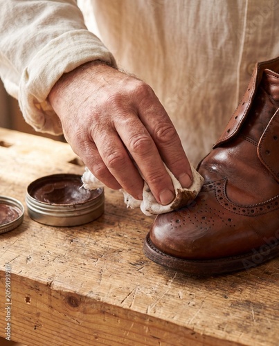 Hand applying brown shoe cream wax polish with cotton cloth to brogue dress shoe