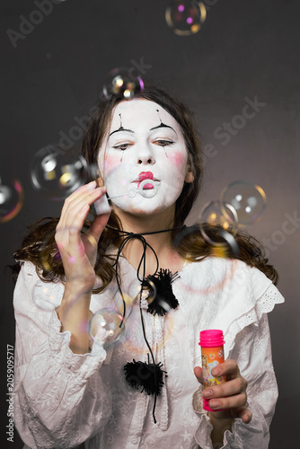 Clown woman with closed eyes blowing soap bubbles in dreamlike portrait