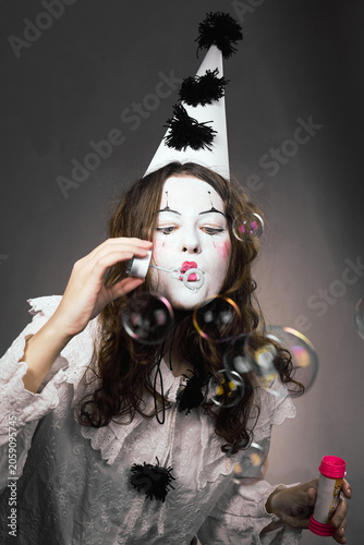 Clown woman puckering lips to blow soap bubbles in a studio portrait