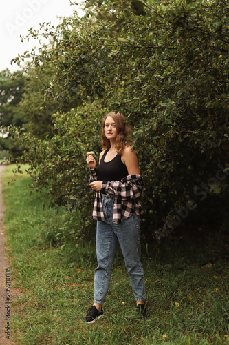 A walk through a country garden: a girl holding a green apple.