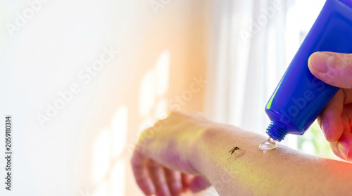 Person applying ointment on arm to relieve mosquito bite  