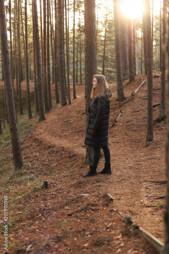 Girl in autumn pine forest at sunset