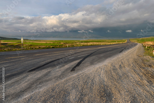 Long tire skid marks on rural road beneath dramatic storm clouds. Road safety concept.