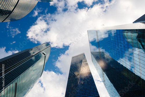 Photography Tall glass skyscrapers of business offices in city reflect blue sky, clouds, and other skyscrapers
