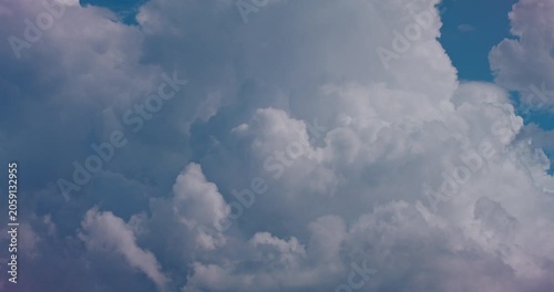 Bright cumulus clouds drifting across a calm blue sky in soft daylight