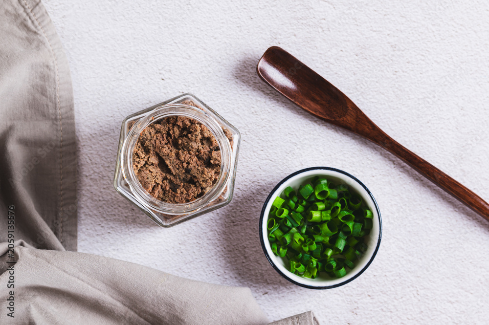 Fototapeta premium Liver pate in a jar and green onions in a bowl on the table top view