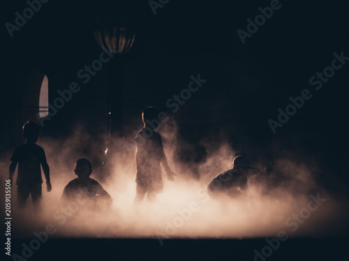 Silhouette of children playing in the thick fog at twilight