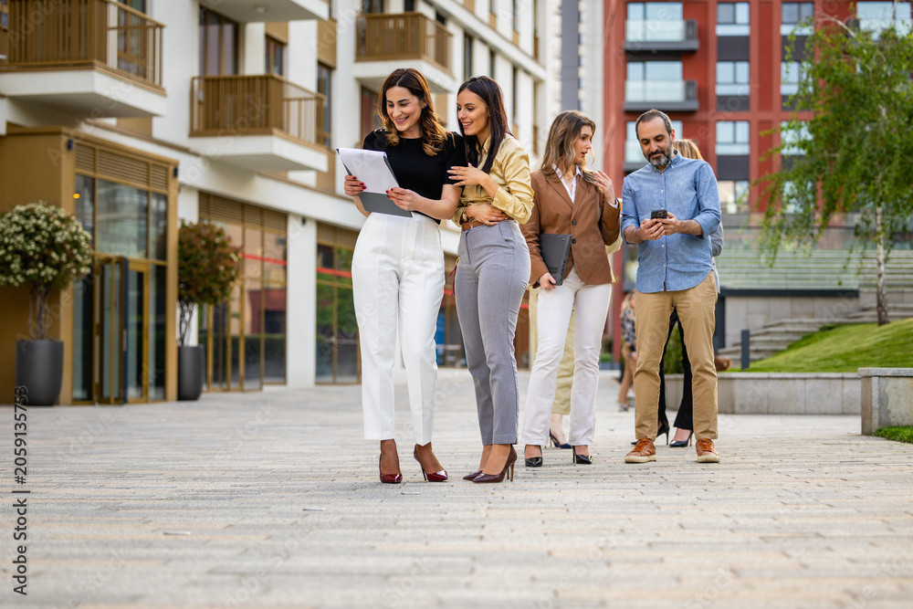 Fototapeta premium Business colleagues walking and discussing documents outside modern office building