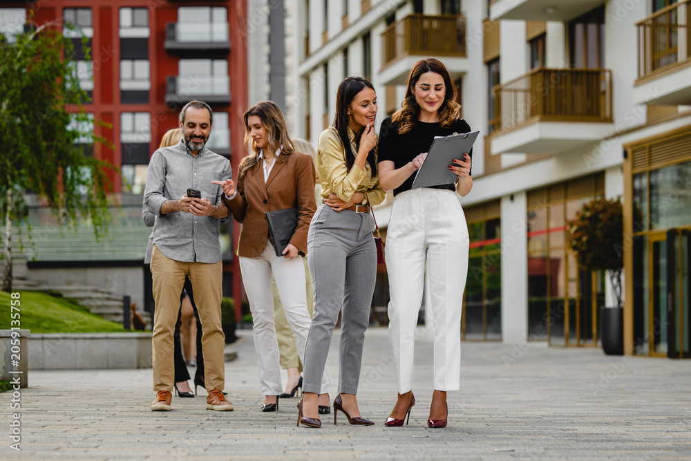 Fototapeta premium Business colleagues walking and discussing documents outside a modern office building during a casual team meeting