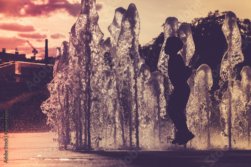 Children playing in a fountain at sunset