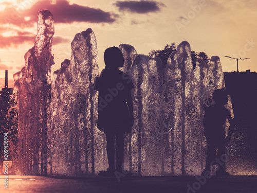 Children playing in a fountain at sunset