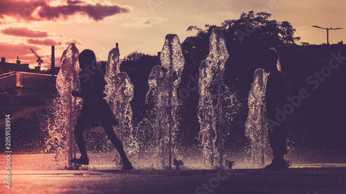 Children playing in a fountain at sunset