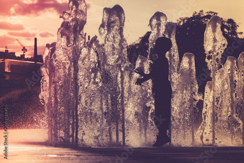 Children playing in a fountain at sunset