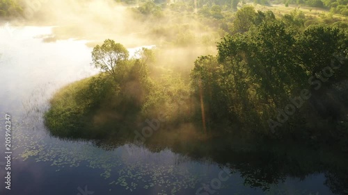 Misty morning landscape with river and trees in golden sunlight, 4K drone shot