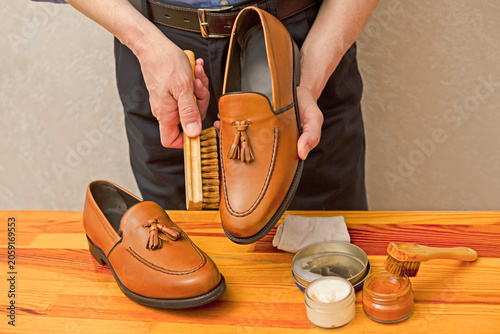 Hands of Professional Male Shoes Cleaner with Cleaning Shoe Wax, Cream and Brushes For Tan Calf Leather Tassel Loafers Shoes
