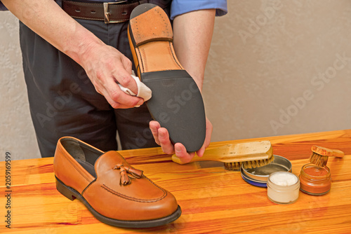 Hands of Professional Male Shoes Cleaner with Cleaning Accessories Shoe Wax, Cream and Brushes For Tan Calf Leather Tassel Loafers Shoes